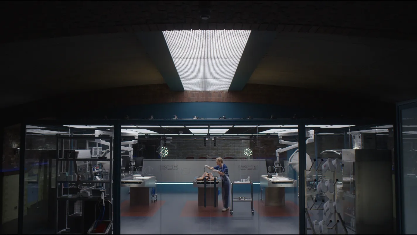 Medical professional standing over a table in a modern laboratory with surgical equipment and bright overhead lighting.